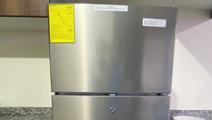 A stainless steel refrigerator with a water dispenser, located in a kitchen with granite countertops and wooden cabinets.