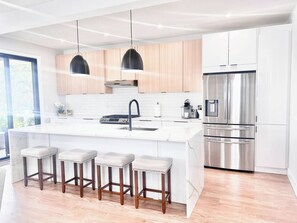 A modern kitchen with a central island, stainless steel appliances, and wooden bar stools. - 1 Block To The Beach -NEW House (Manasquan)