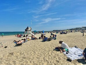 A beach with people sunbathing and relaxing on the sand.