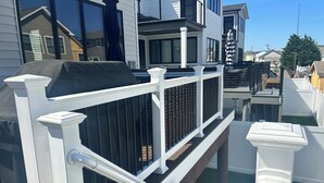 A residential building with a white balcony railing, a black awning, and a clear sky.