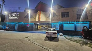 Un hotel con un cartel que dice "HOTEL AEROPUERTO" y un estacionamiento con coches.