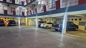 Un aparcamiento interior de varios niveles, con una mezcla de coches y todoterrenos estacionados bajo áreas techadas.
