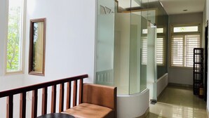 Un moderno vestíbulo de hotel con un separador de vidrio curvo, un banco de madera y una pequeña mesa.