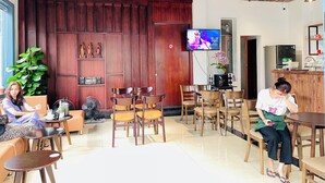 Un área de descanso moderna con paneles de madera, un televisor de pantalla plana y diferentes opciones de asientos, incluyendo sillas y un sofá.