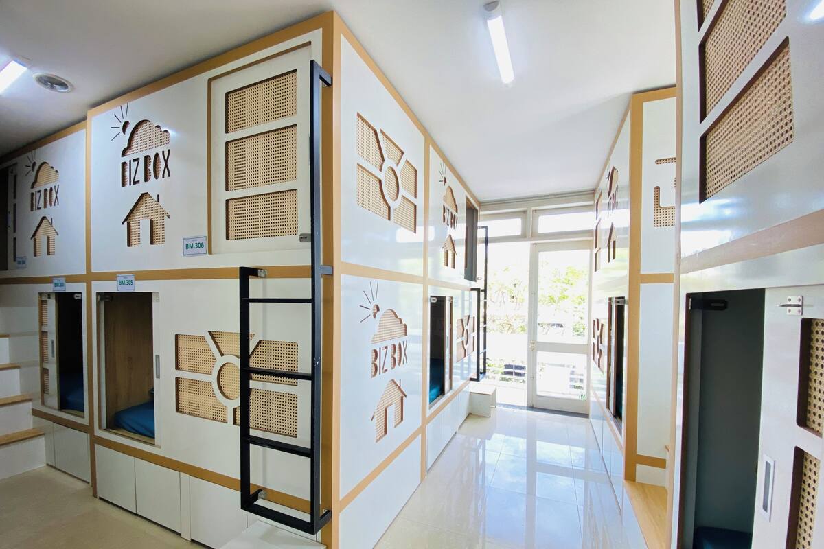 Un pasillo de hotel con varias habitaciones, cada una con un número único y un pequeño ventanal.