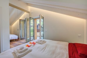Een slaapkamer met een bed, een rode deken en een glazen deur naar een balkon.