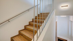 Una escala moderna amb graons de fusta i baranes metàl·liques, que condueix a un pis superior.