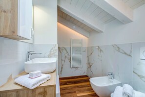 A modern bathroom with a wooden vanity, a large white sink, a bidet, and a freestanding bathtub. - Cimetta, Livigno, Italy (Livigno)