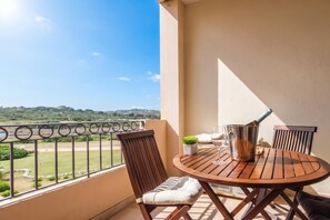 Un balcone con tavolo, sedie, un secchio di metallo e una pianta in vaso.
