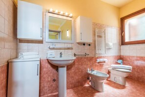 Un baño con lavamanos, espejo, armario, toallero y retrete.