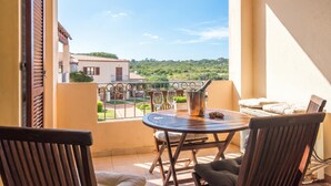 Ein Balkon mit Tisch, Stühlen und Blick auf eine grüne Landschaft.
