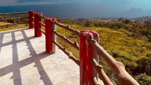 Un chemin en béton, bordé de rambardes rouges, mène à un belvédère offrant une vue panoramique.