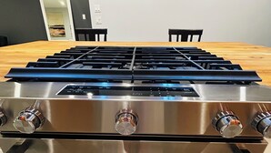 En spishäll i rostfritt stål med fyra brännare, en inbyggd ugn och en kontrollpanel.