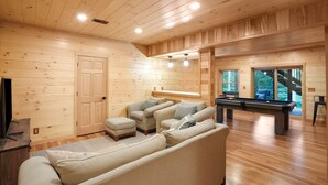 A wooden interior with a sofa, ottoman, and pool table. - Rustic Ravine | Hocking Hills, Hot Tub, Game Room (South Bloomingville)