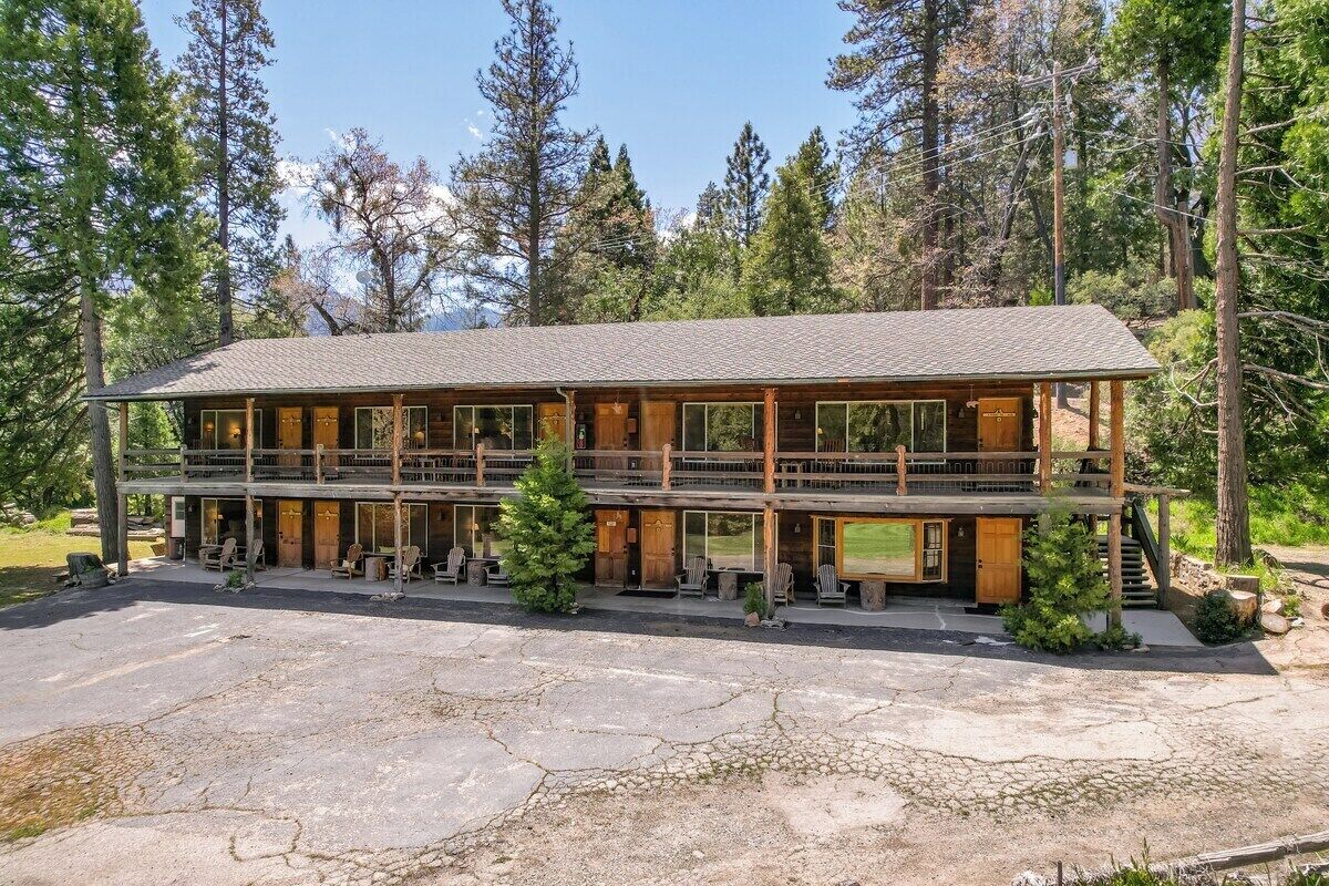 A two-story lodge with a wooden exterior, multiple windows, and a stone-paved entrance.
