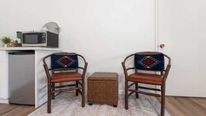 A small kitchenette with a microwave, a refrigerator, and a small table with chairs.