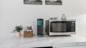 A kitchen counter with a microwave, a Keurig coffee maker, a basket of items, and a potted plant. - Suite Meadow Camp Nelson Lodge# 7 (Springville)