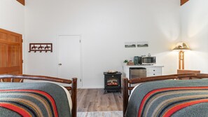 A cozy room with two wooden chairs, a small black stove, a microwave, and a lamp. - Suite Meadow Camp Nelson Lodge# 7 (Springville)