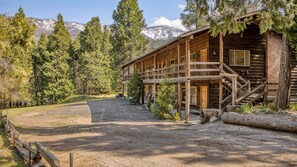 A rustic lodge with a wooden exterior, a covered porch, and a staircase leading to the entrance. - Suite Meadow Camp Nelson Lodge# 7 (Springville)