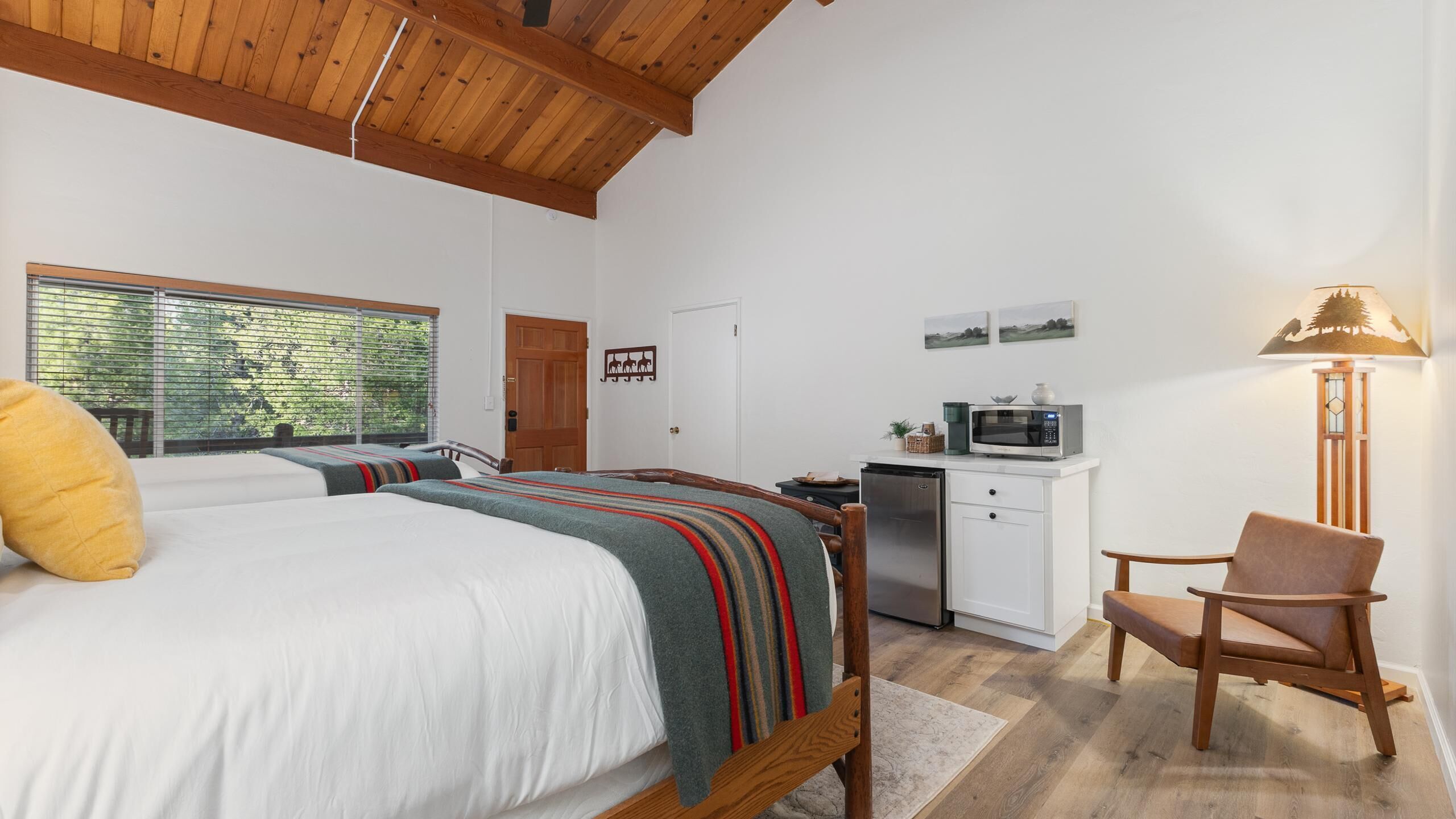 Une chambre avec un lit, un bureau, une chaise, un four à micro-ondes et une porte.