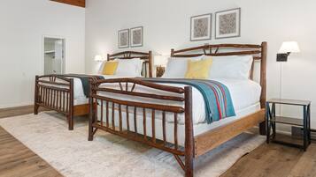 A bedroom with two wooden beds, a white rug, and a small table.