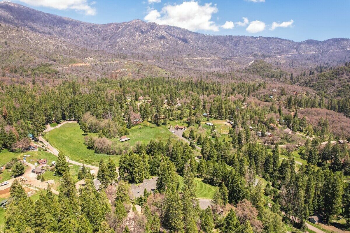 A mountainous landscape with scattered residential buildings, a golf course, and dense forest areas.