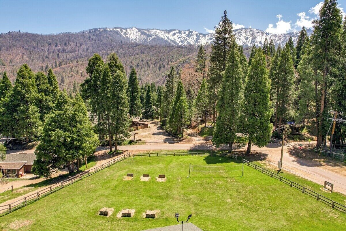 Un área verde con un cerramiento, una estructura de madera y montañas al fondo.