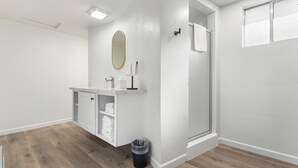 A bathroom with a shower, a toilet, a sink with a mirror, and a towel rack. - Camp Nelson Lodge Room 9 (Springville)