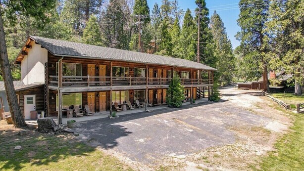A two-story lodge with a covered porch and outdoor seating area. - Camp Nelson Lodge Room 9 (Springville)