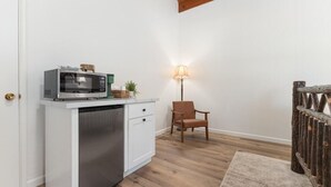 A compact kitchen with a microwave, a small cabinet, a chair, and a lamp. - Camp Nelson Lodge Room 9 (Springville)