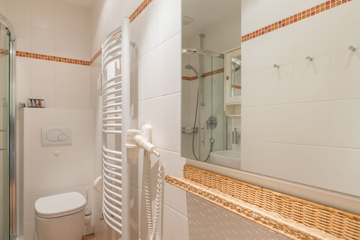 Et badeværelse med toilet, bruser og et håndklædestativ.