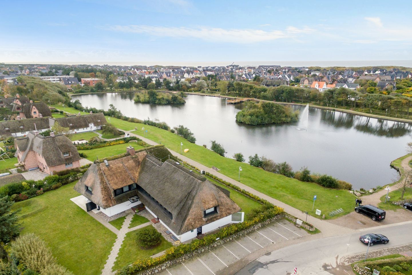 A riverside village with traditional houses, a parking area, and a view of the river.