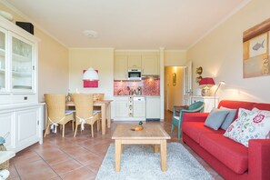 Un espacio habitable compacto con comedor, cocina y un sofá rojo.