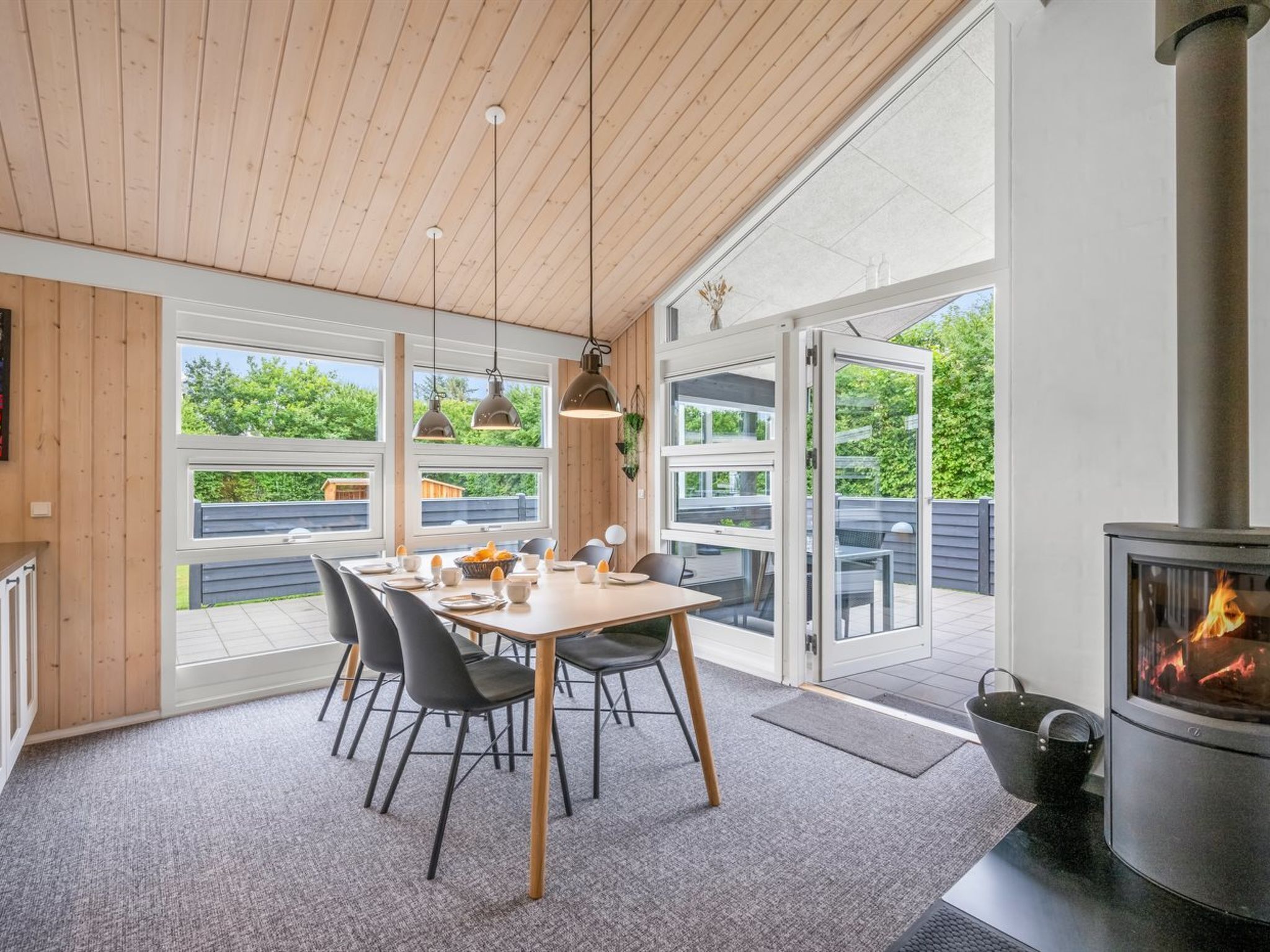 Un comedor moderno con una mesa de madera, sillas e iluminación colgante.