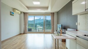 A spacious room with a large sliding glass door leading to a balcony with a mountain view. - Gapyeong Yeonkkocchosu Pet Pension (Gapyeong)