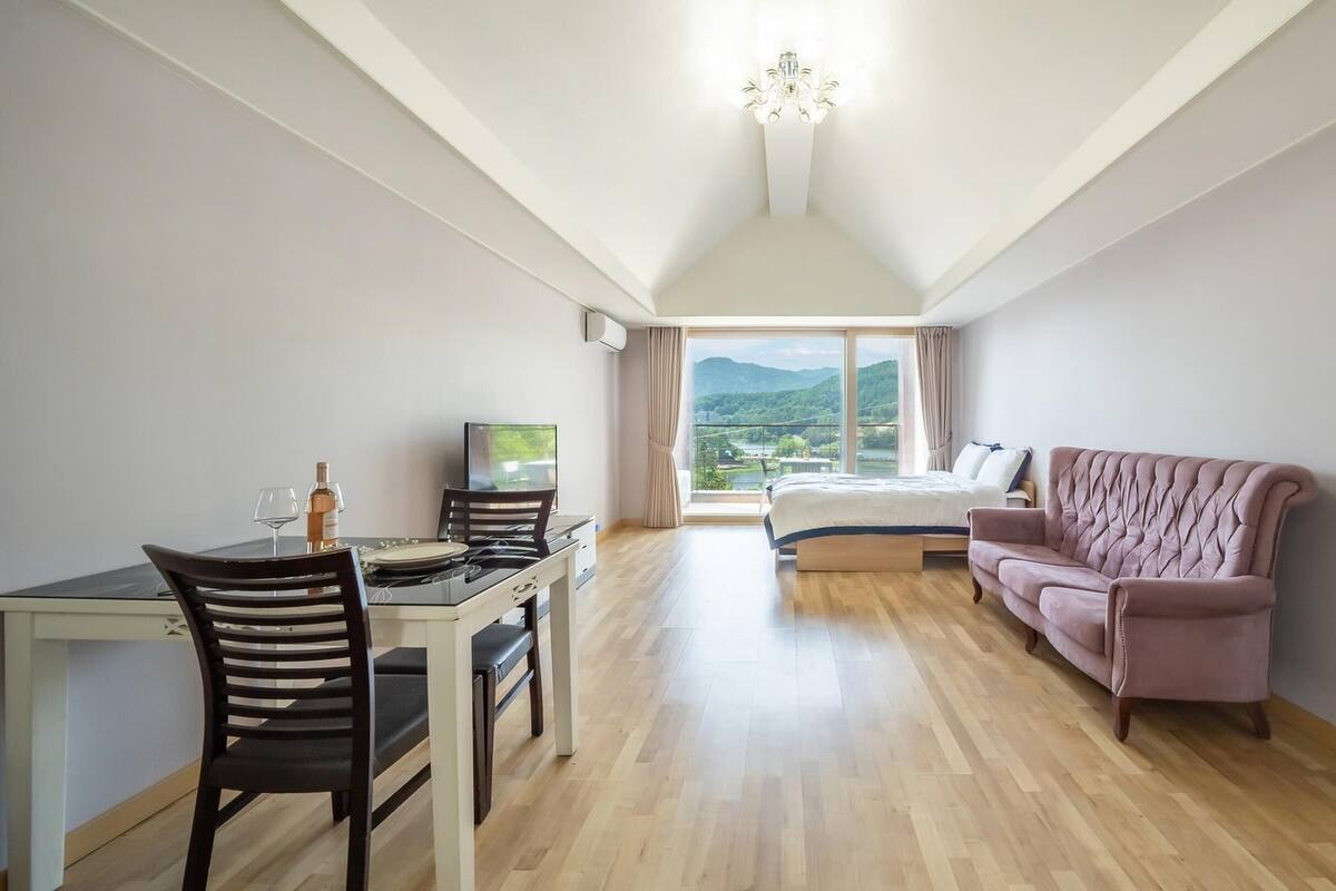 A room with a dining table, chairs, a TV, a bed, and a couch.