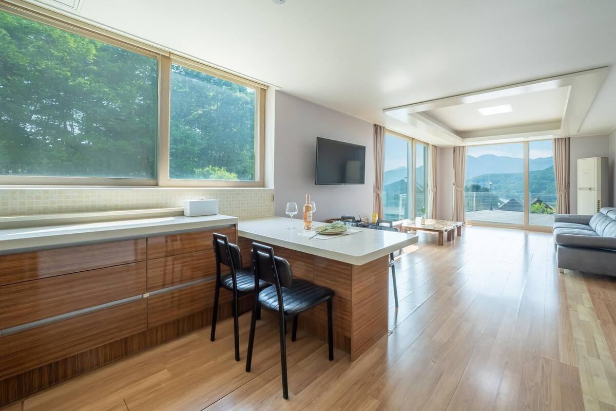 A modern kitchen with a central island, dining area, and a sofa.