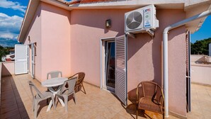 A pink building with a tiled patio, a table with chairs, and an air conditioning unit. - Bonvie Apartments in Center B3 (Novalja)