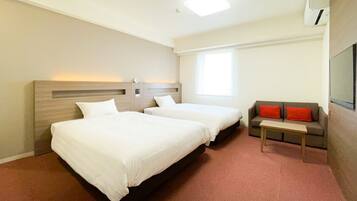 A hotel room with two beds, a sofa, a small table, and a TV.