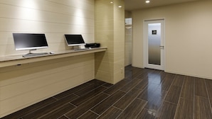 A reception area with two computer stations, a tiled floor, and a door with a sign indicating a smoking area. - Hotel Green Core Bando (Bando)