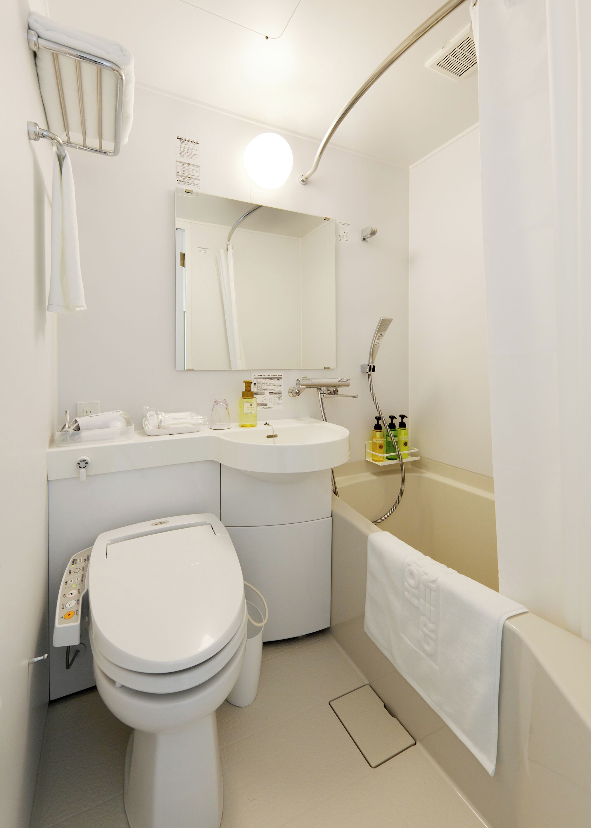 A modern bathroom with a toilet, sink, mirror, shower, and a towel rack.