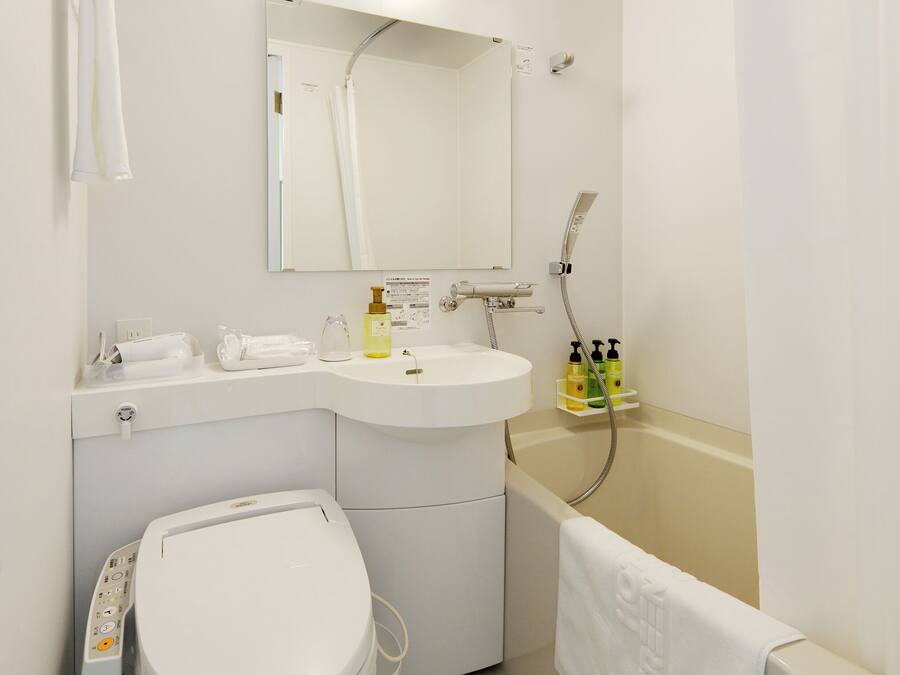 A modern bathroom with a toilet, sink, mirror, shower, and a towel rack.