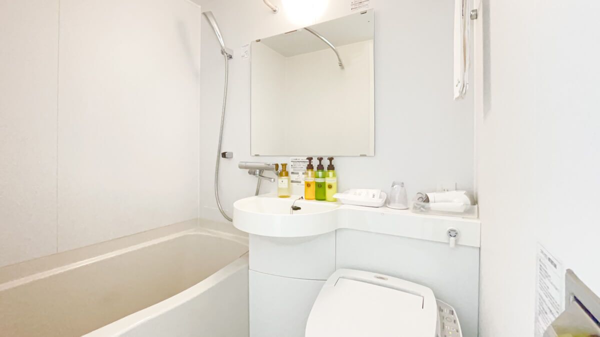 A bathroom with a bathtub, a sink, a toilet, and a mirror.