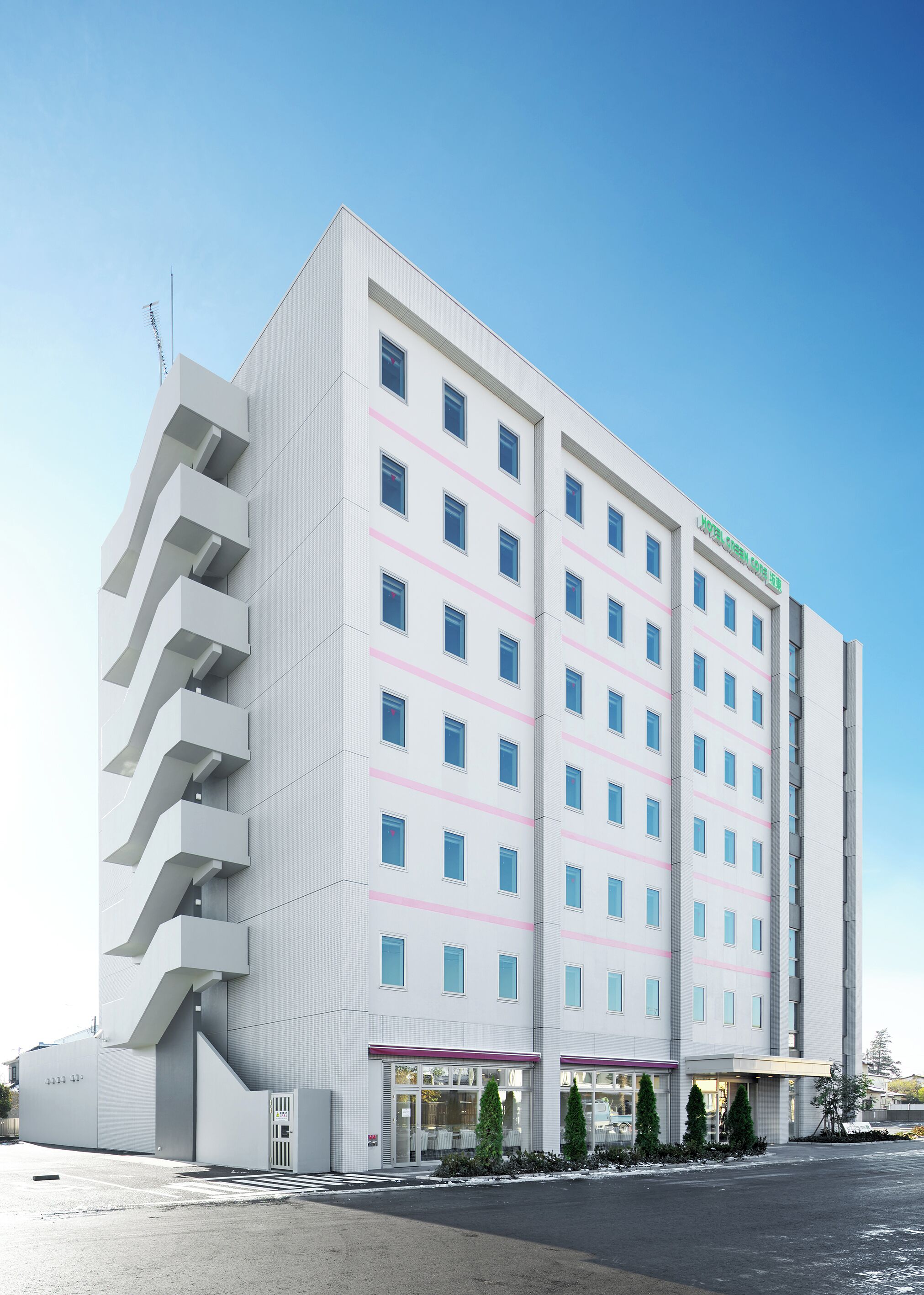 A multi-story hotel with a modern design, featuring a prominent entrance with a covered area and a parking lot in front.
