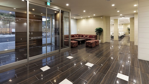 A modern lobby with a glass entrance, a seating area with patterned sofas, and a clean, tiled floor. - Hotel Green Core Bando (Bando)