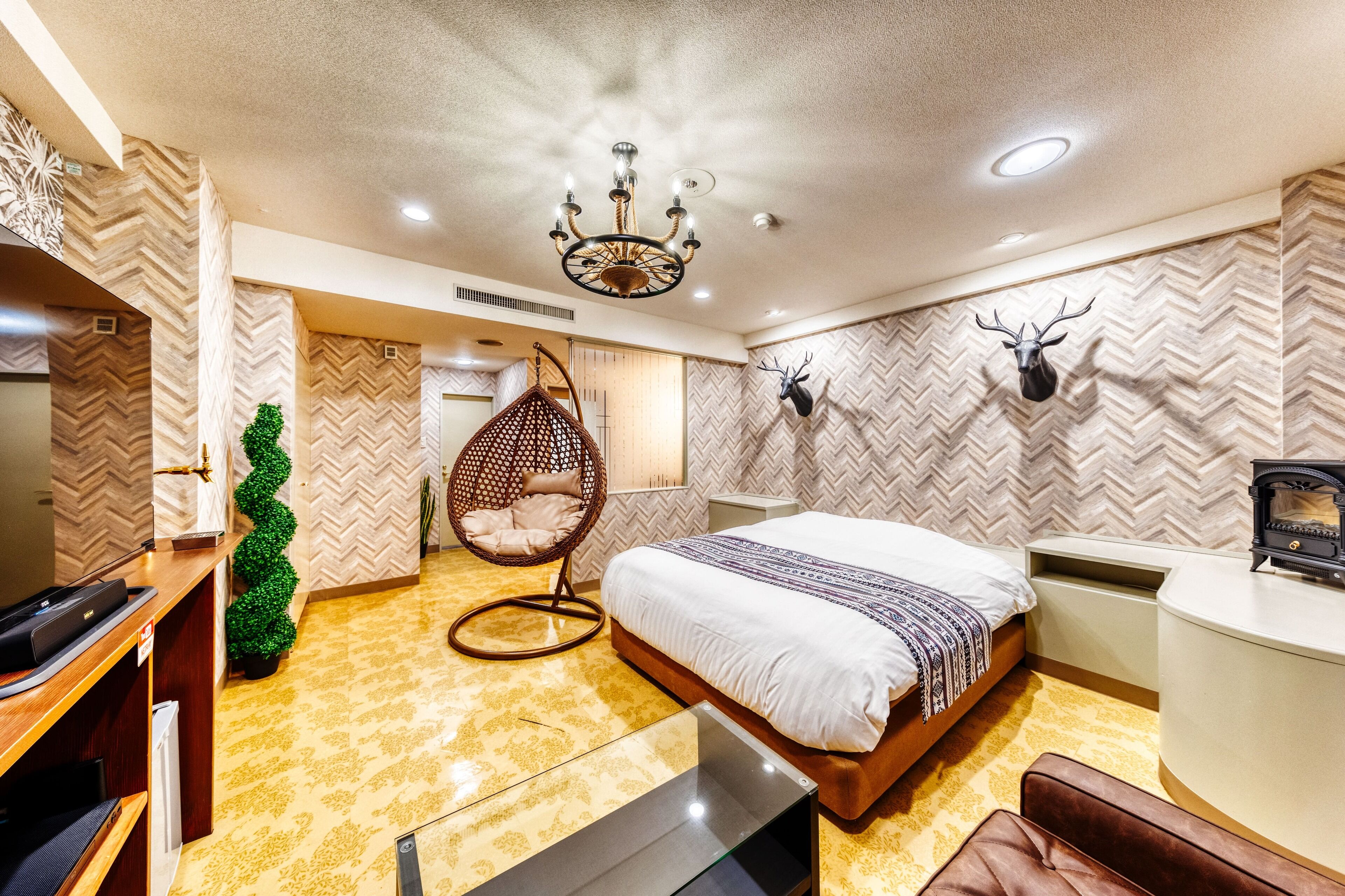 Ein modernes Hotelzimmer mit Bett, Hängesessel, Schreibtisch und Kamin.