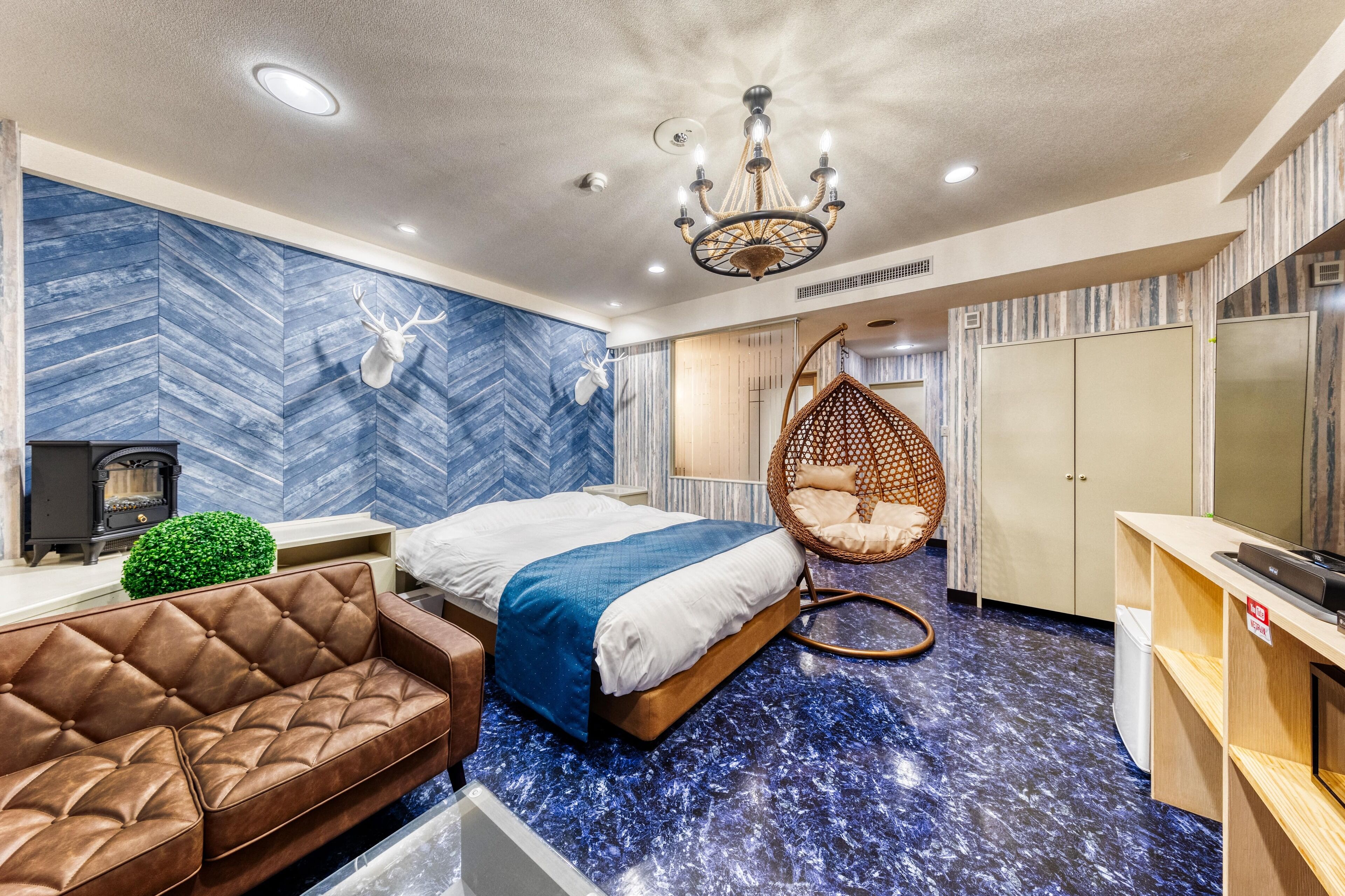 A modern bedroom with a bed, a hanging chair, a sofa, and a television.