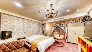 A modern bedroom with a tufted leather sofa, a hanging chair, a bed with a white and gold bedspread, a wardrobe, and a television on a wooden stand. - Hotel Lotus morioka - Adult Only (Shizukuishi)
