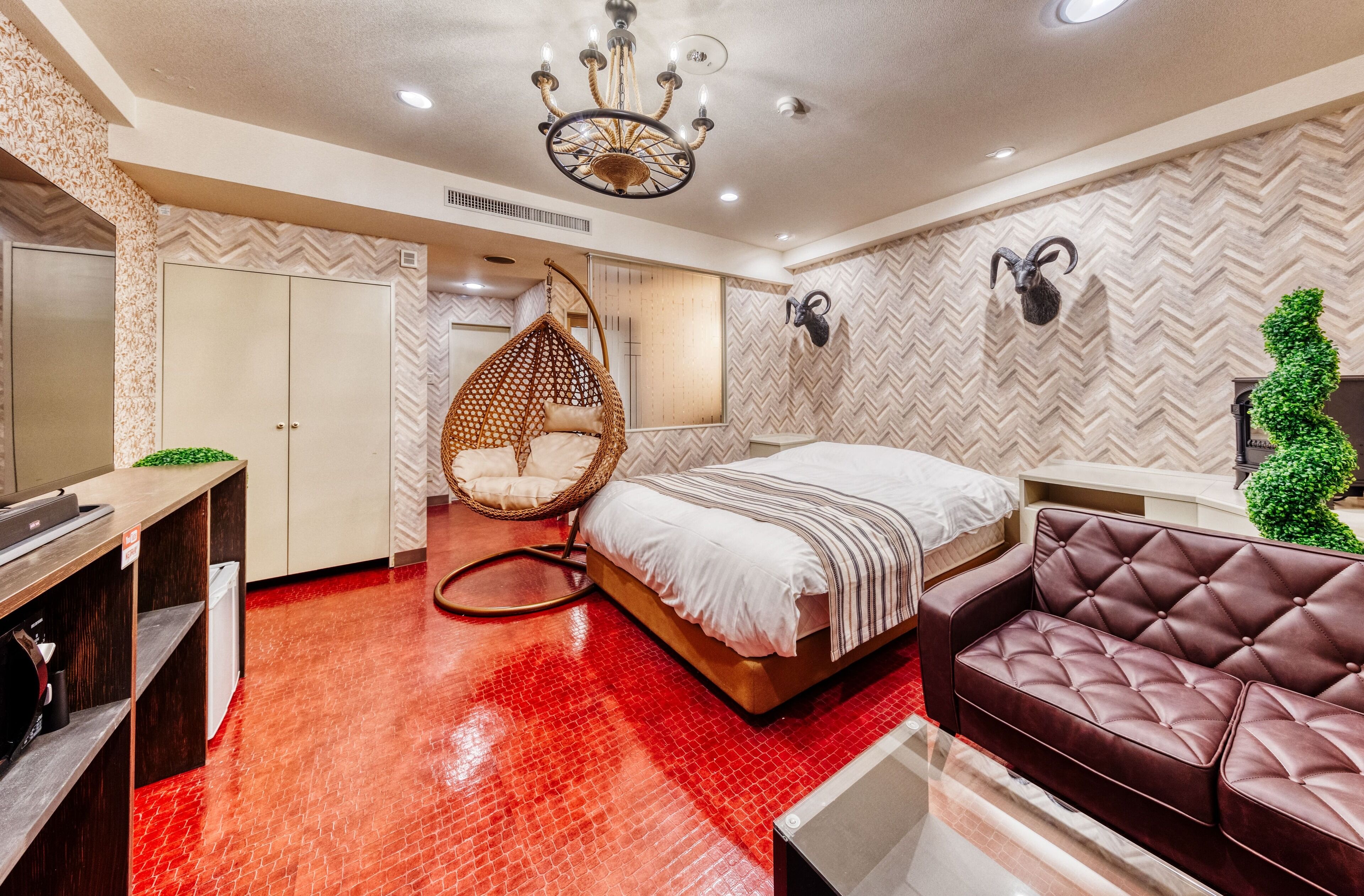 Een moderne slaapkamer met een bed, een hangstoel, een bank en een garderobe.