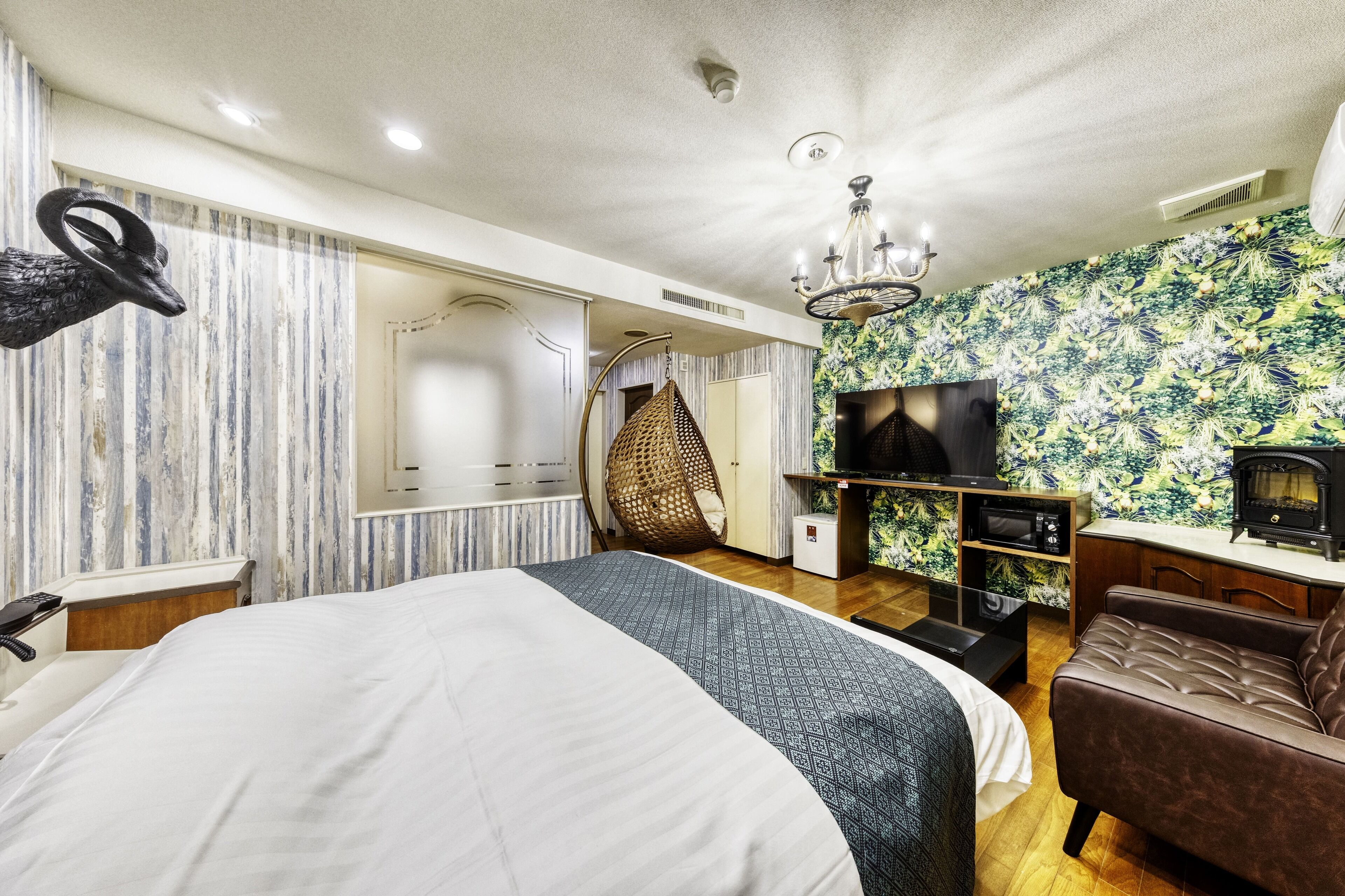 Een moderne hotelkamer met een groot bed, een televisie, een bank en een decoratieve wand.